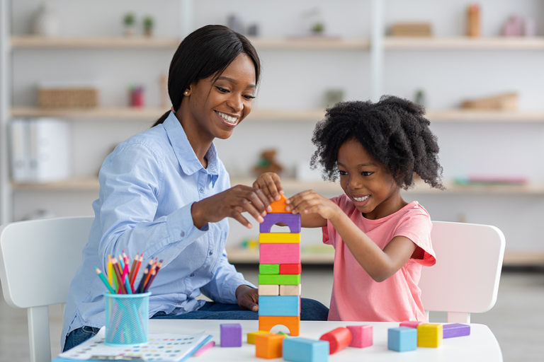 Adorable Black Kid And Child Development Specialist Playing With